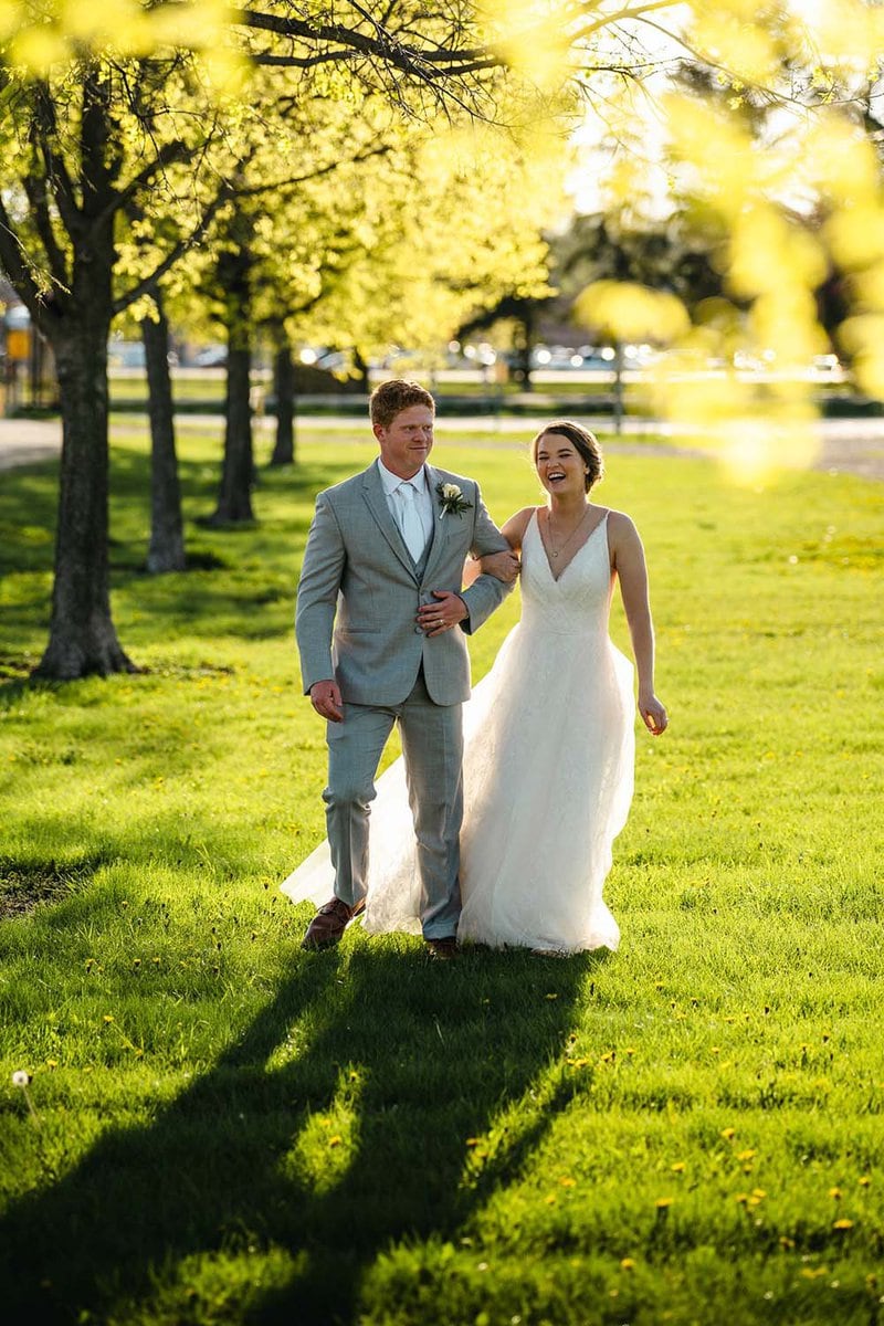 Adirondack Photography A Bride And Groom Walking Through A Park.